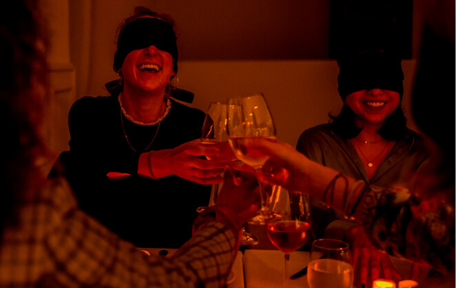 Des convvives trinques les yeux bandés lors de l'expérience culinaire Dining In The Dark