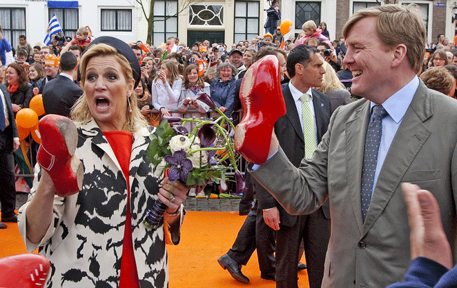 Le roi Willem-Alexander et la reine Maxima des Pays-Bas avec des sabots rouges sur les mains pendant une fête folklorique