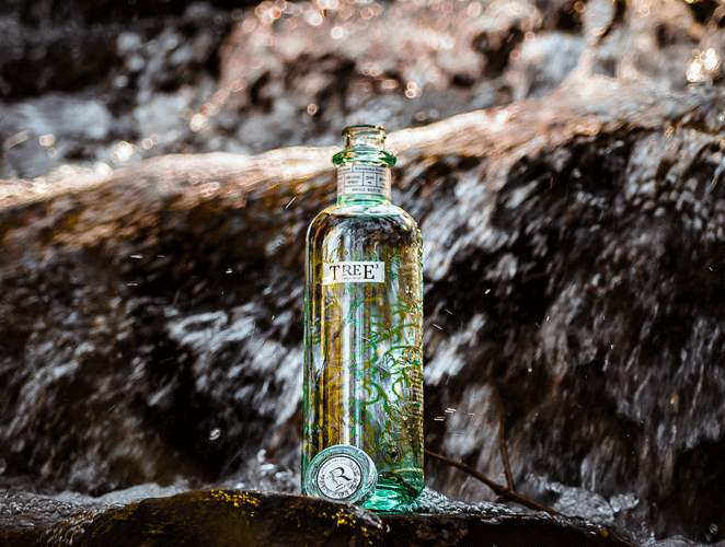 Une bouteille du gin biologique Tree3 dans une chute d'eau